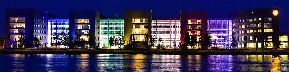 Un ensemble de bâtiments de bureaux allumés se reflète sur l'eau la nuit